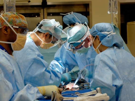 Doctors performing surgery on a patient laying on a table.