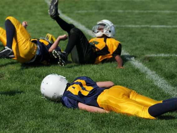 children laying on ground while playing football