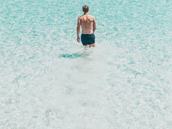 Man wearing dark colored shorts in clear, blue water
