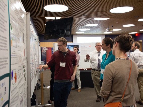 person speaking in front of a research poster