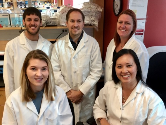 Doyle lab members wearing white lab coats smiling in the lab