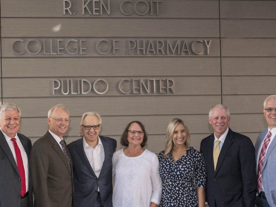 Arizona Board of Regents' Ron Shoopman, College of Pharmacy Dean Dr. Rick G. Schnellmann, R. Ken Coit, Donna Coit, Lauryn Coit Ackley, UArizona President Dr. Robert C. Robbins and UArizona Foundation President and CEO JP Roczniak stand in front of the just-unveiled R. Ken Coit College of Pharmacy signage.