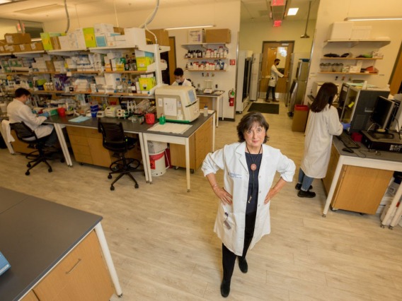Dr. Brinton standing in a lab with researchers working behind her
