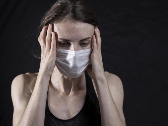 Woman wearing mask with a headache.