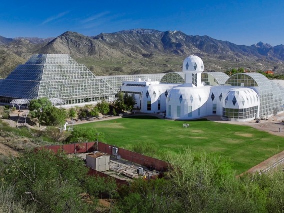 Arial shot of Biosphere 2, a glass-domed and pyramid structure in the middle of green desert and mountains