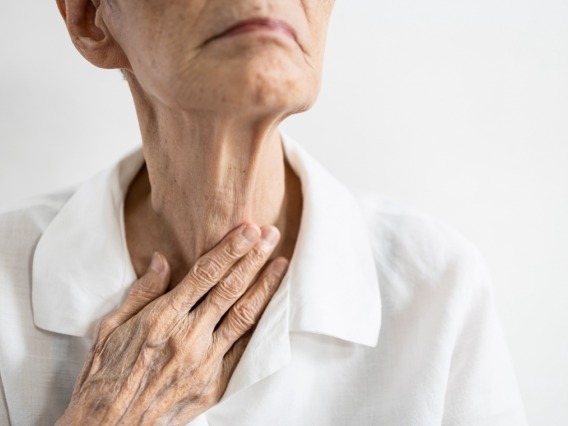 Elderly woman holding her neck.