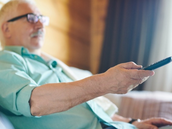 Elderly man holding TV remote