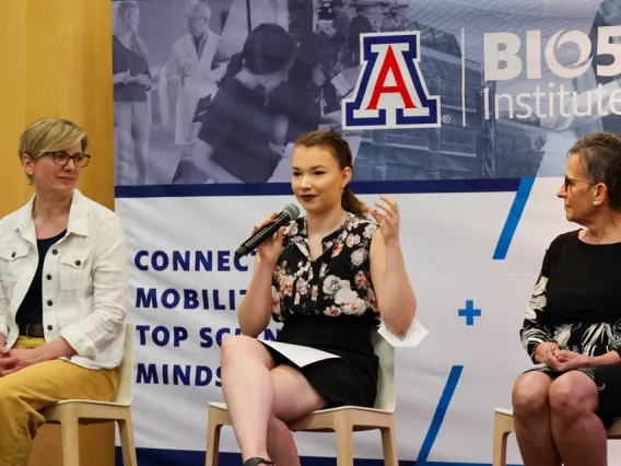 Three people speaking to a group at an event