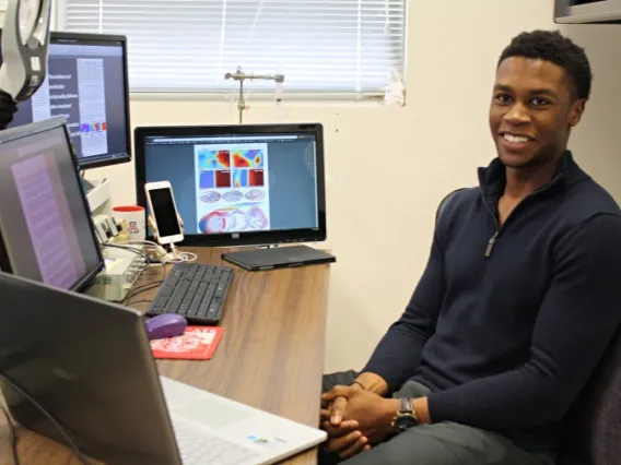 Young person in blue shirt sits in front of a computer