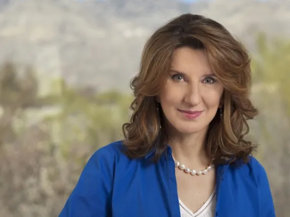 Woman in blue shirt with desert landscape behind her