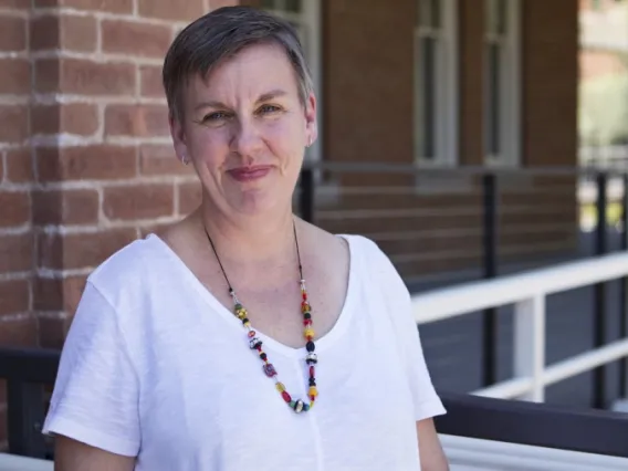 Short-haired woman with a colorful beaded necklace and wearing a white shirt