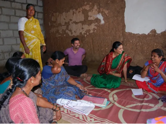 Group of women in traditional Indian clothes sitting on the ground and socializing