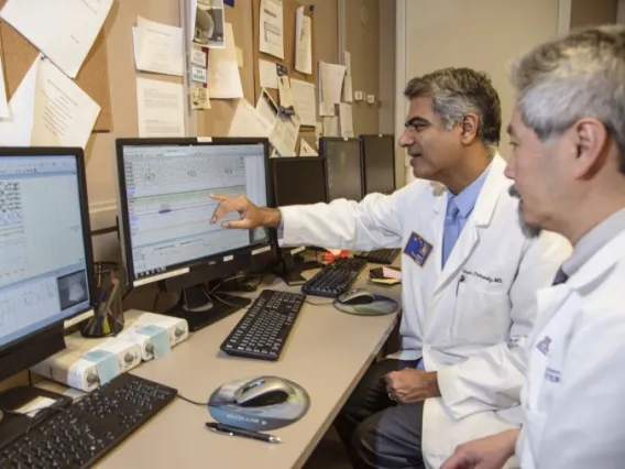 Two physician-scientists work together as one points to a computer screen