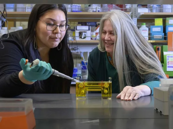 Angel-Grace Charity Leslie is pipetting under the supervision of Kathleen Rodgers, PhD