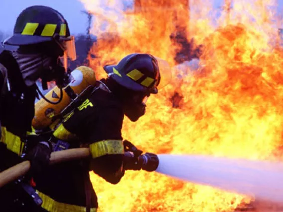 Firefighters fighting a fire with a large hose