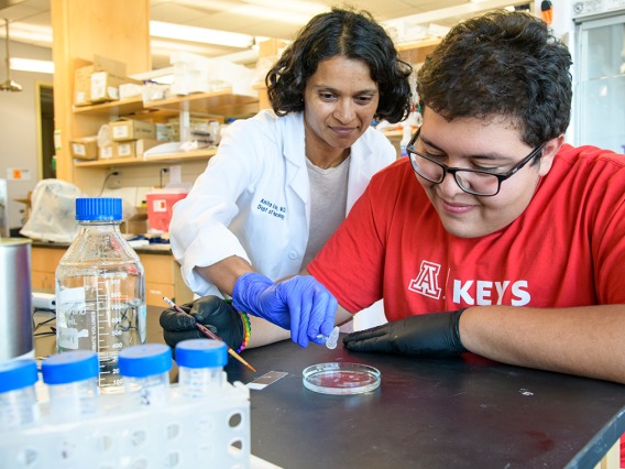A high school student working with a researcher in a lab