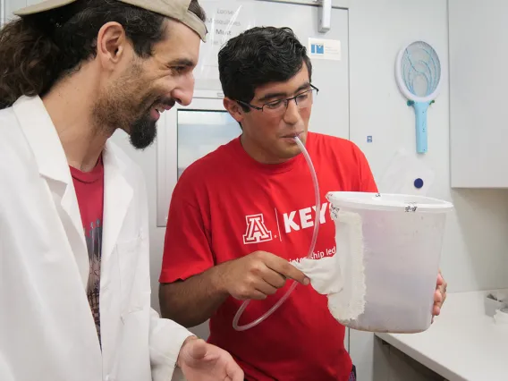 high school student working with a researcher in a lab