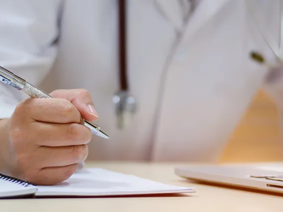 a clinician holding a pen and writing on paper