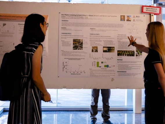 Two individuals are viewing and discussing scientific posters at a conference.