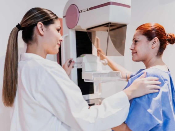 A medical professional assists a patient with a mammogram examination in a clinic.