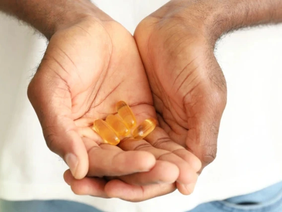 Person holding a handful of omega-3 supplement capsules.