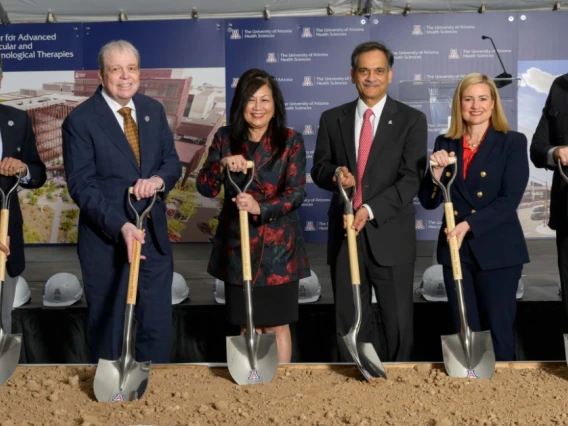 A group of people in professional attire holding shovels for a breaking ground ceremony