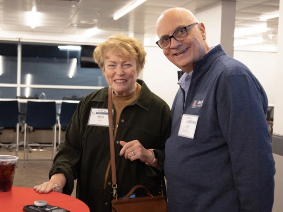 Two individuals, Marie Wesselhoft and Uwe Hilgert, smiling at a networking event with beverages on a red table.