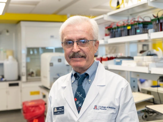 A person wearing a lab coat with a "College of Medicine, Phoenix" badge standing in a laboratory setting