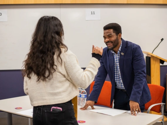 Person smiling and chatting with another person across a table in at Student Industry Networking Event.