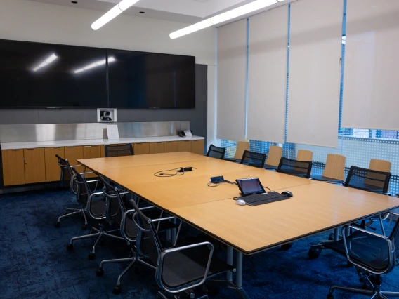 Modern conference room with a large table, several chairs, and a presentation screen on the wall