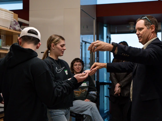 A group of students participates in a hands-on demonstration led by an scientist in a laboratory setting.