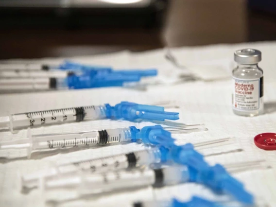 Syringes and a vial labeled 'COVID-19 Vaccine' arranged on a table.