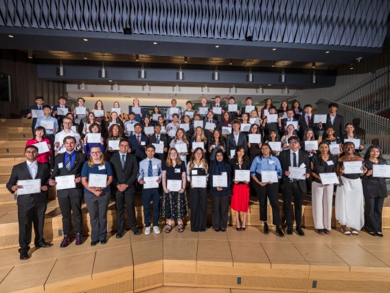 Group of individuals holding certificates in a tiered auditorium.