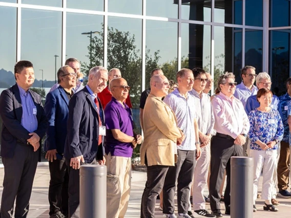 A group of professionals standing outside a modern building with large glass windows, under clear skies.
