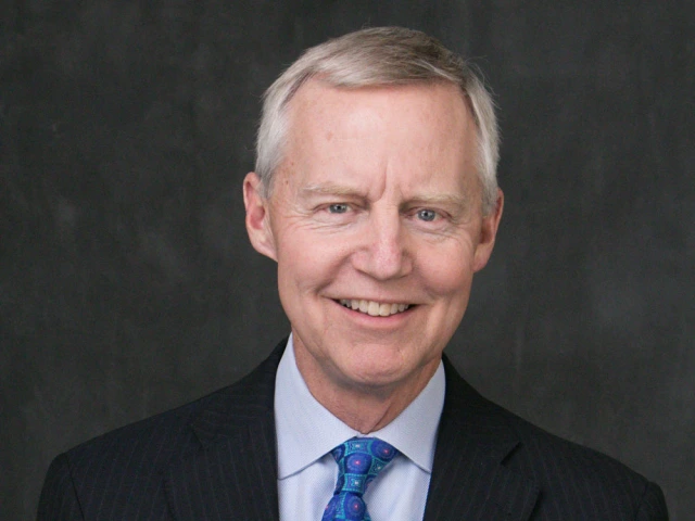 Portrait of a person smiling in a black suit and blue tie.