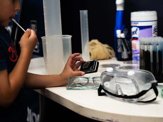 Child examining magnifying glass at photo booth prop table
