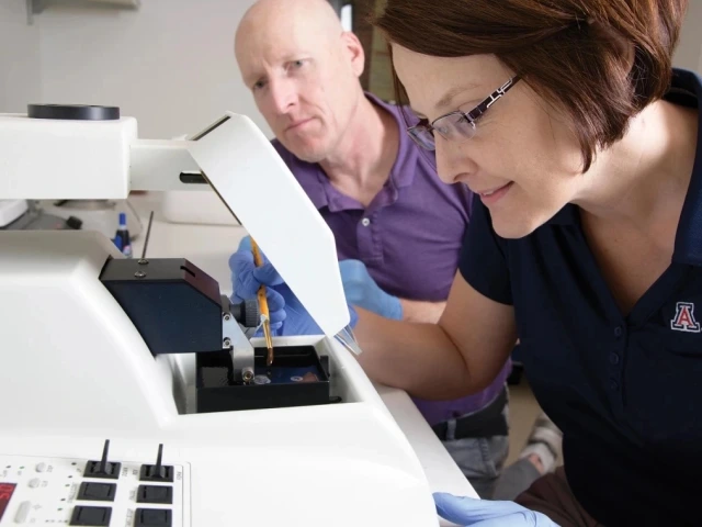 Two scientists using specialized laboratory equipment at the University of Arizona, Agricultural and Life Sciences facility.