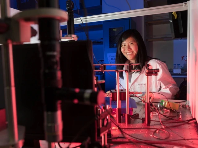 A woman smiling next to a lab with red lights.