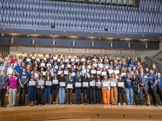 Group of students standing with certificates in the auditorium