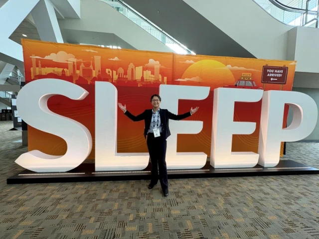 Person stands in front of orange and white sign spelling SLEEP