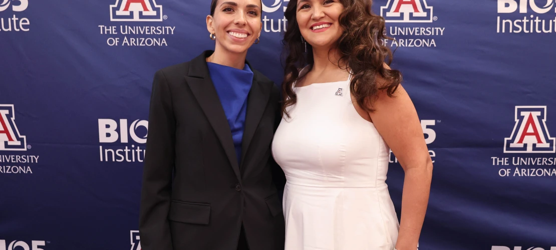Two women pose in front of a sign with the BIO5 Institute logo