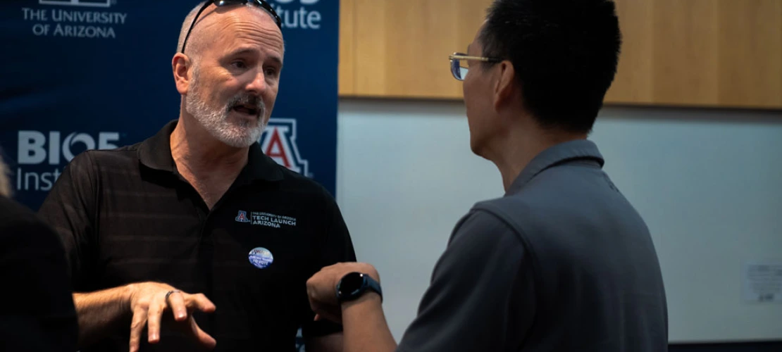 Two individuals are engaged in a conversation at a University of Arizona BIO5 Institute event.
