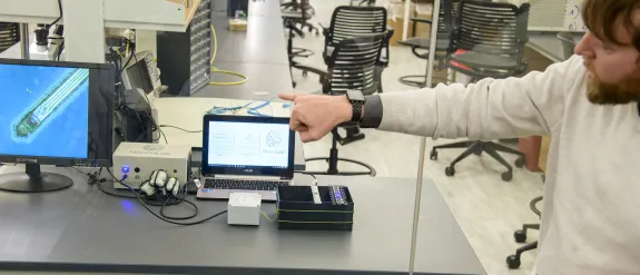 a researcher explaining a how a piece of scientific equipment works