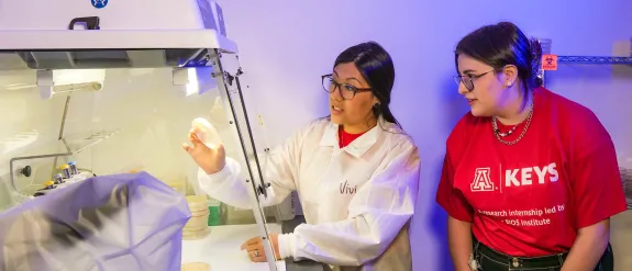 A woman researcher showing a petri dish to a student in a lab setting