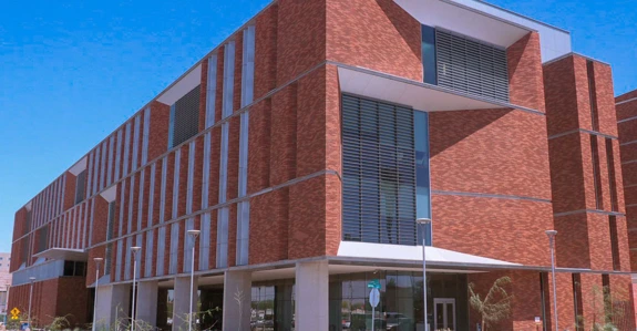 Exterior view of the modern brick building with large windows and multiple levels, under a clear blue sky.