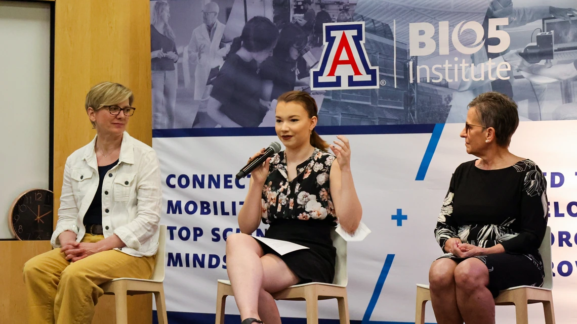 Three people speaking to a group at an event