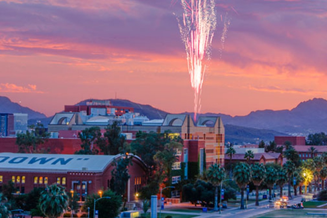 a long shot view of the university of arizona campus during a sunset with fireworks