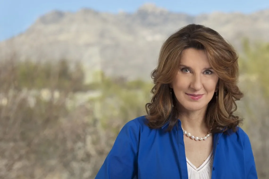 Woman in blue shirt with desert landscape behind her