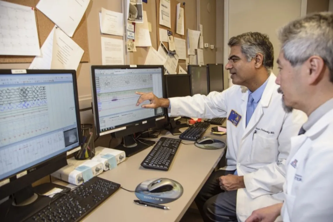 Two physician-scientists work together as one points to a computer screen