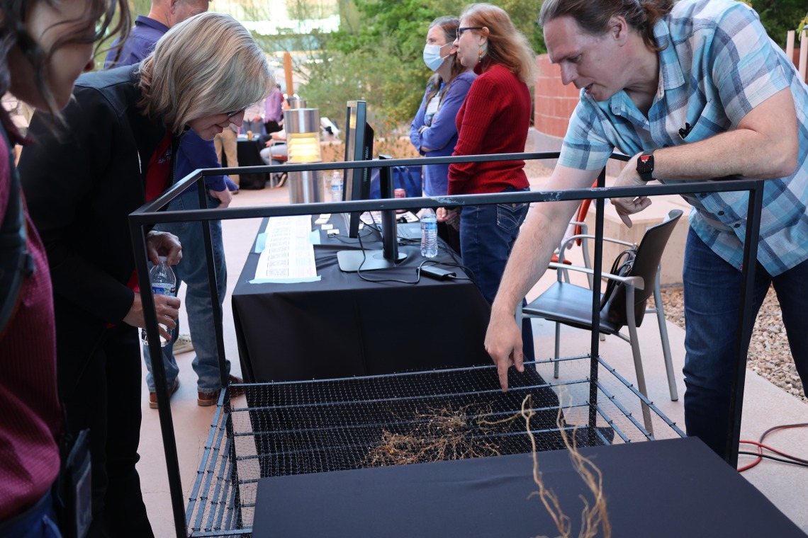 Man points to root structure at his research demonstration table